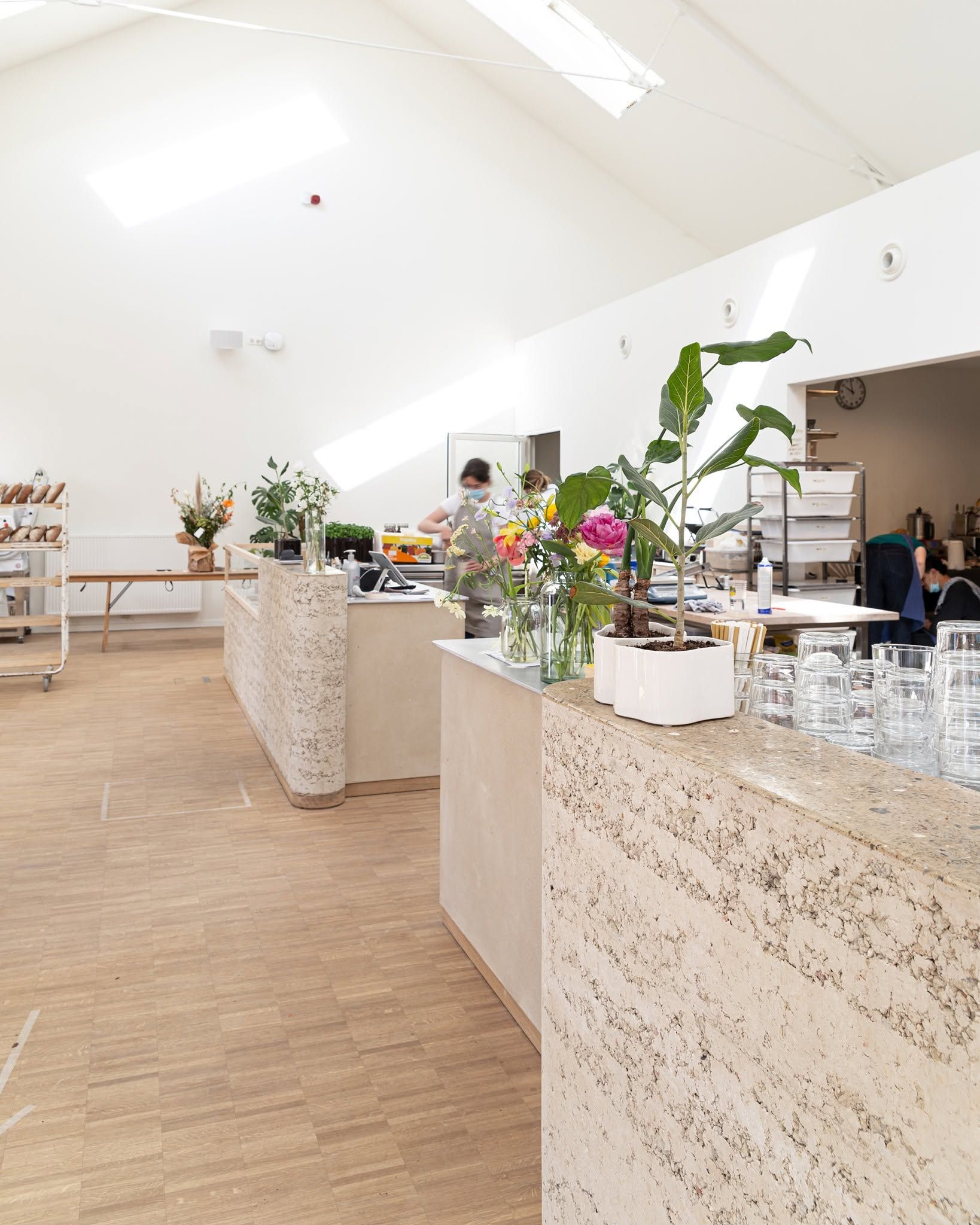 Lichtrijk interieur van nives met terrazzo toonbank, verse bloemen en houten vloer