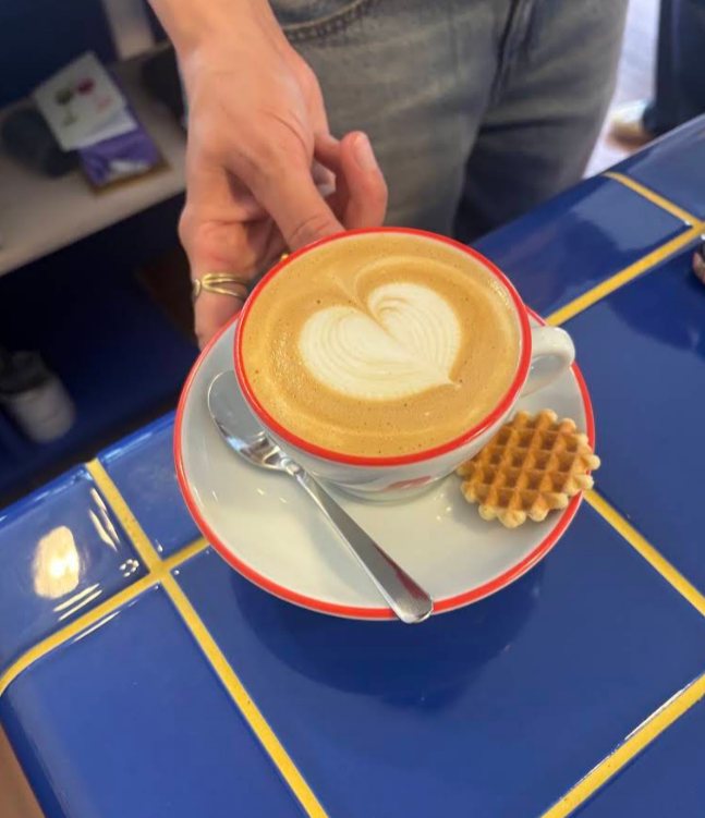 Cappuccino met latte art en een wafel, geserveerd op de blauwe tegelbar van Polette