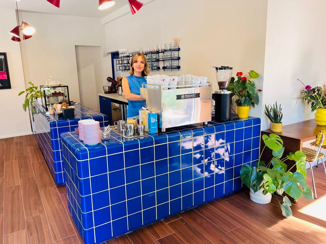 Paulien achter de blauwe tegelbar van Polette met de espressomachine en verse bloemen