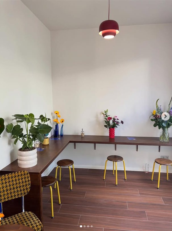 Zithoek bij Polette met gele krukjes, verse bloemen en een houten bar